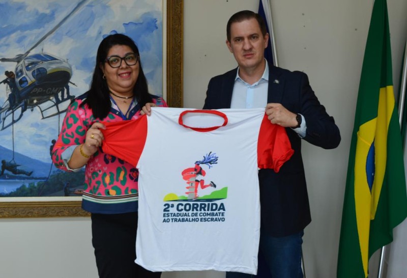 A vice-presidente da Coetrae, Márcia Ourives, entregou ao secretário de Segurança Pública, coronel PM Roveri, a camiseta e o regulamento da corrida - Foto por: Willian Silva