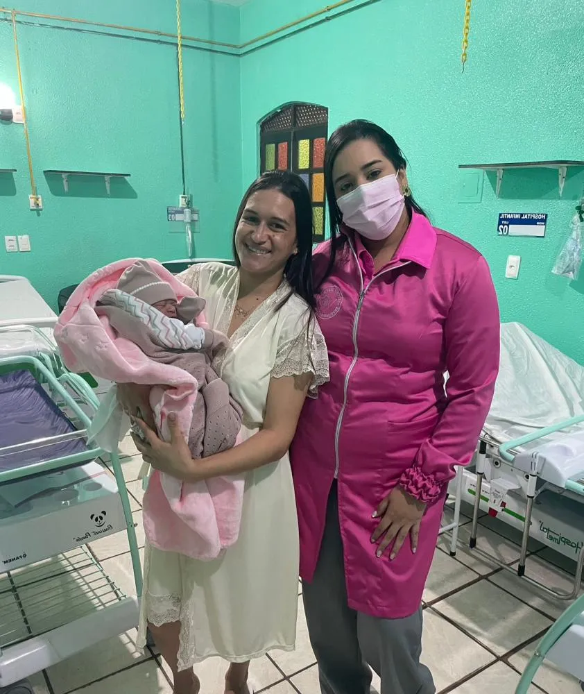 Foto da enfermeira e da parturiente com sua filha recém-nascida no Hospital e Maternidade Palmira Sales