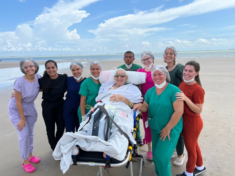 Rodeado pela família e equipe multiprofissional, o aposentado José Pinheiro pôde satisfazer a vontade de ver o mar e sentir o calor do sol (Foto: Divulgação) - Rodeado pela família e equipe multiprofissional, o aposentado José Pinheiro pôde satisfazer a v